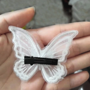 Detail of white lace butterfly hair clip featuring a black metal duckbill clip