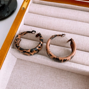 Close-up of leopard print C-shape hoop earrings with glossy resin finish on jewelry tray