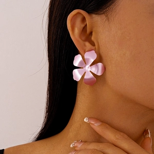 Macro detail of a large matte pink 5-petal flower statement earring worn by a model