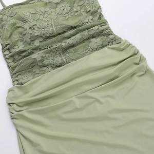 Close-up of light green lace embroidery and pleated fabric stitching on the slim dress