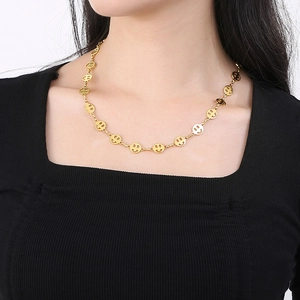 Close-up of golden hollow smile face chain necklace worn on neck for women