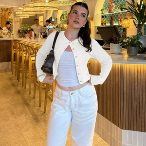Gros plan sur la maille du cardigan blanc avec boutons et coupe ajustée à manches longues