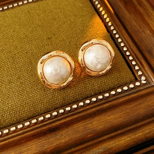 Macro view of gold-plated cotton pearl round earrings with elegant wave metal base