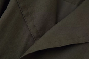 Gros plan du tissu sergé vert olive foncé montrant les coutures de précision et la texture