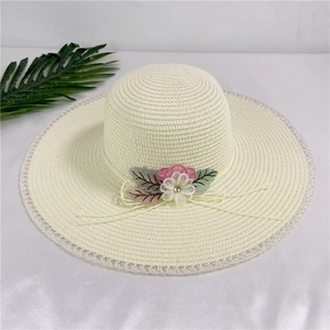 Detail of white wide-brim straw hat with lace edges and pink floral decorative accents