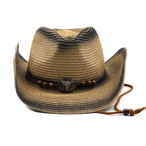 Close-up of vintage straw cowboy hat with metallic bull skull and braided rope detail