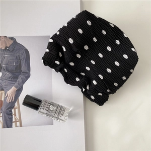 Detail shot of black polka dot pleated cosmetic bag on minimalist white background