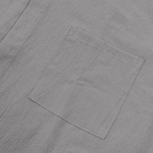 Detail view of grey linen fabric texture and stitching on the shirt breast pocket