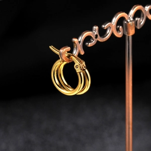 Macro shot of small gold polished stainless steel huggie earrings on a vintage stand