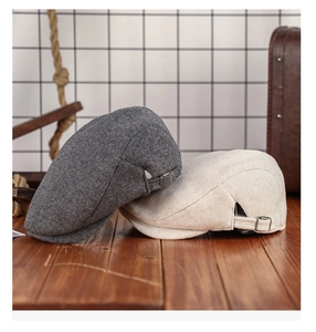 Detailed view of dark grey and beige wool newsboy caps on a rustic wooden desk