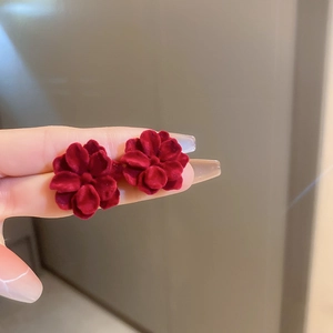 Close-up of red flocked flower earrings with velvet texture shown on fingers