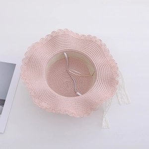 Pink straw sun hat for women with wavy brim and elegant white lace ribbon tie