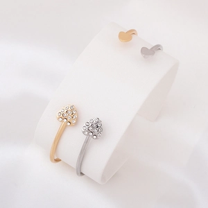 Close-up of gold and silver heart-shaped bracelets with sparkling crystals on silk background