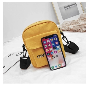 Detail of yellow canvas crossbody bag featuring black CHAO print and adjustable strap