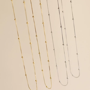 Detailed view of snake bone bead necklaces in gold and silver stainless steel finishes