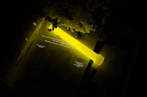 Close-up of a glowing yellow emergency glow stick with hook design on aesthetic background
