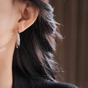 Close-up of a model wearing stylish silver teardrop hoop earrings with a sleek metallic finish