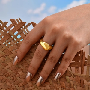 Close-up of a wide gold teardrop ring featuring a liquid metal design worn on a finger
