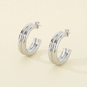 Detail of silver C-shaped hoop earrings with a textured double-ridged metallic design