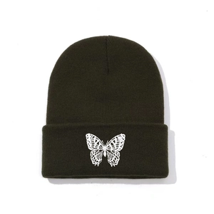 Close-up of a white butterfly embroidery on an olive green ribbed knit beanie hat