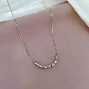Close-up of a silver titanium steel necklace featuring sleek olive-shaped beads on a fine chain
