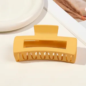 Close-up of a large matte yellow hair claw clip with a hollow rectangular design and grip teeth