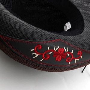 Black woven straw cowboy hat featuring intricate red floral embroidery and leather band