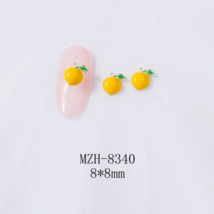 Detail of peach-shaped alloy nail charms with yellow enamel and golden leaf accents