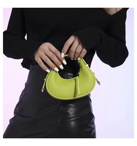 Model holding a fruit green crescent hobo bag with litchi texture and top handle