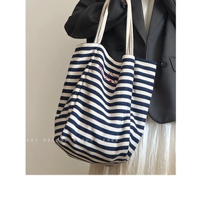 Detail of blue striped canvas tote bag featuring red animal embroidery and rope handles