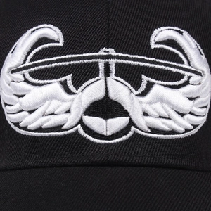 Detailed close-up of white symmetrical eagle wings embroidery on a black cotton baseball cap