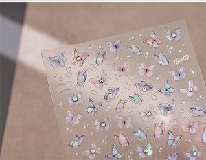 Detailed macro of 3D butterfly nail stickers with iridescent finish and pearl accents