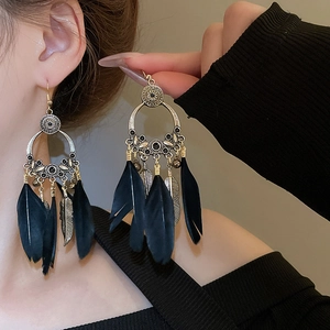 Vue détaillée des boucles d'oreilles bohèmes avec plumes noires et gravures vintage