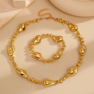 Vue détaillée d'un ensemble de bijoux dorés avec des perles irrégulières sur fond beige