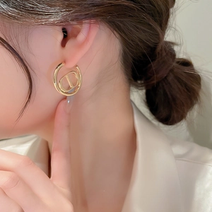 Elegant gold hoop earrings with CD letter design on female model showing a chic style