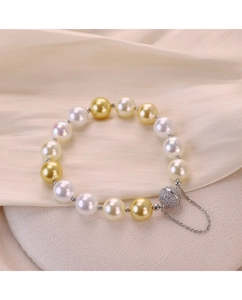 Gros plan du bracelet en perles blanches et dorées avec fermoir magnétique serti