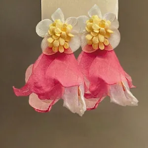 Detailed close-up of 3D layered fabric flower earrings with pink tassels and yellow pistils
