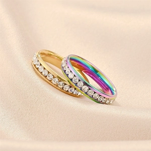 Close-up of gold and rainbow titanium steel rings with encrusted zircon stones
