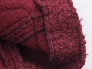 Detailed macro view of burgundy wool boucle fabric texture and precision stitching