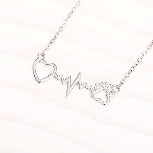 Polished silver heart heartbeat and cat paw pendant necklace on white textured background