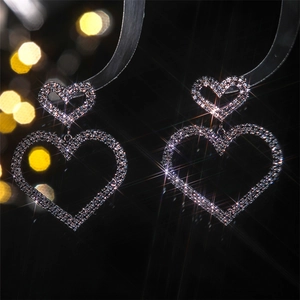 Macro shot of silver heart earrings with sparkling rhinestones on black background