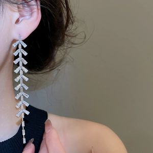 Détail de boucles d'oreilles pendantes en argent avec cristaux et design géométrique de feuilles