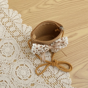 Détail de sac en paille pour enfant avec nœud floral et dentelle sur bois