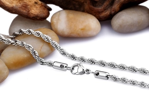Close-up of silver twist chain necklace with lobster clasp over natural pebbles