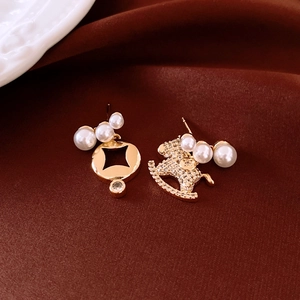 Detail of 18K gold horse earrings with pearls and rhinestones on red silk background
