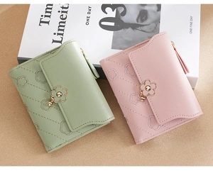 Detail of light green and pink PU leather wallets with quilted floral patterns and metal buckle