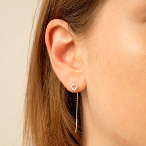 Close-up of heart-shaped diamond-studded silver tassel chain earring worn by a model