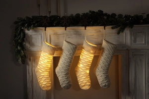 Close-up of knitted Christmas stockings with LED lights hanging on a rustic mantelpiece