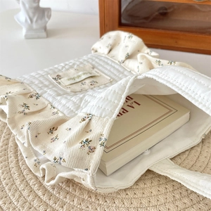 Detail view of the cream floral quilted tote bag with ruffles and magnetic closure