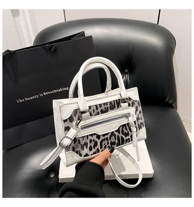 Detalle del bolso blanco con panel de estampado de leopardo y cremallera metálica elegante